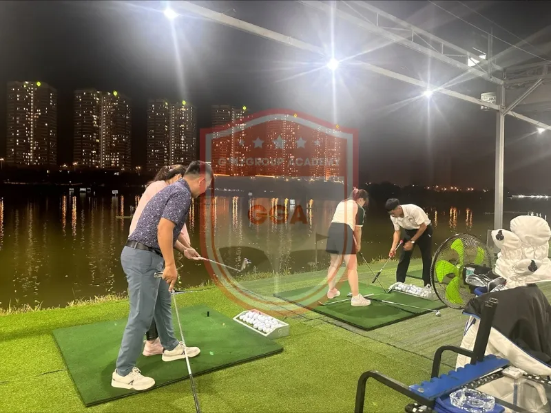 Một nhóm người đang tập golf trong phòng mô phỏng, thể hiện sự linh hoạt trong phương pháp huấn luyện và học tập. Điều này gợi liên tưởng đến việc sử dụng các công cụ khác nhau để nắm bắt handicap trong bóng đá và các chiến lược soi kèo.