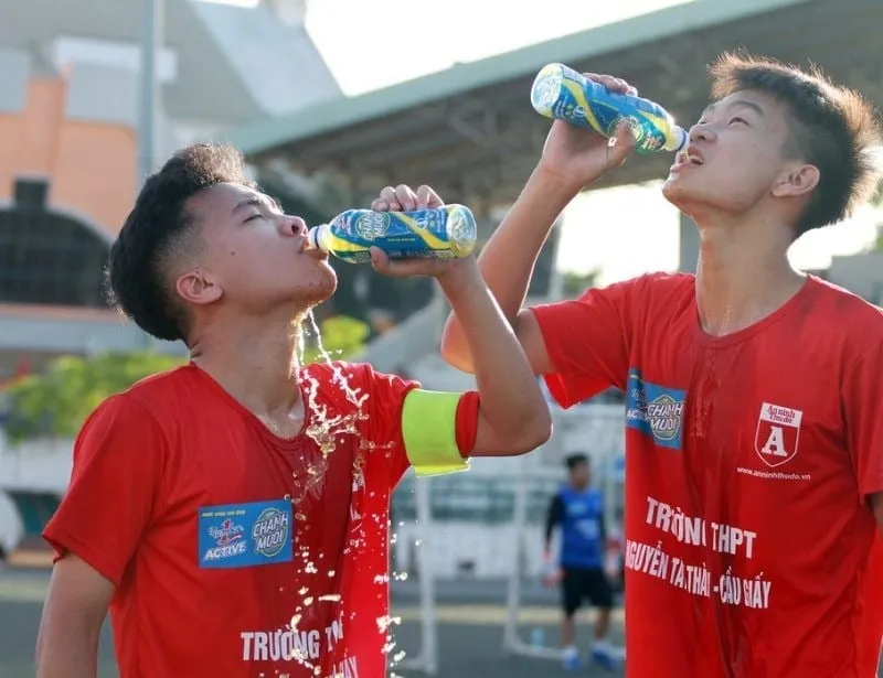Chân của một cầu thủ đang được mát xa nhẹ nhàng, trong khi đó một chai nước điện giải đang được đặt cạnh, minh họa tầm quan trọng của việc bù nước và thư giãn sau khi đá bóng xong cần làm gì