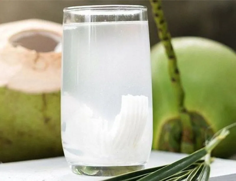 Một cầu thủ uống nước dừa tươi để bù nước và điện giải sau khi luyện tập, hỗ trợ tăng cường hiệu suất trên sân bóng